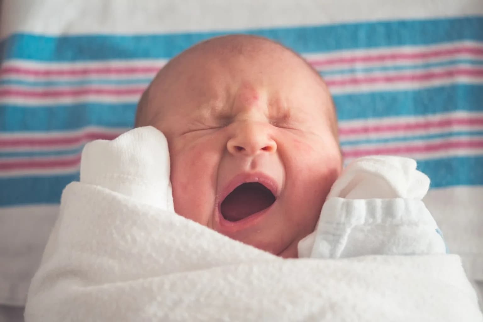 A newborn baby looking upward shortly after birth in a hospital setting