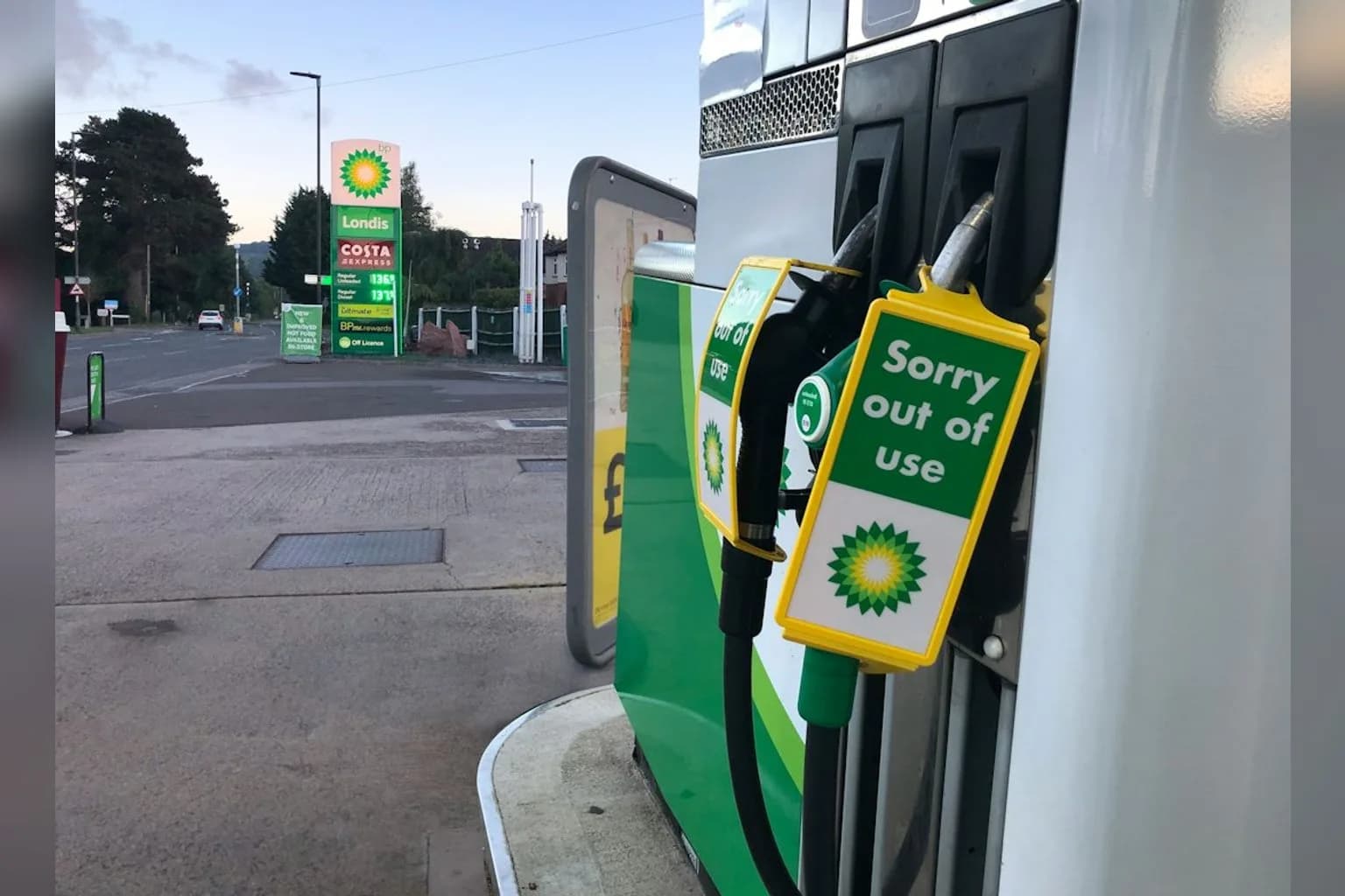 A diesel pump nozzle at a UK filling station with a price display board showing elevated diesel costs
