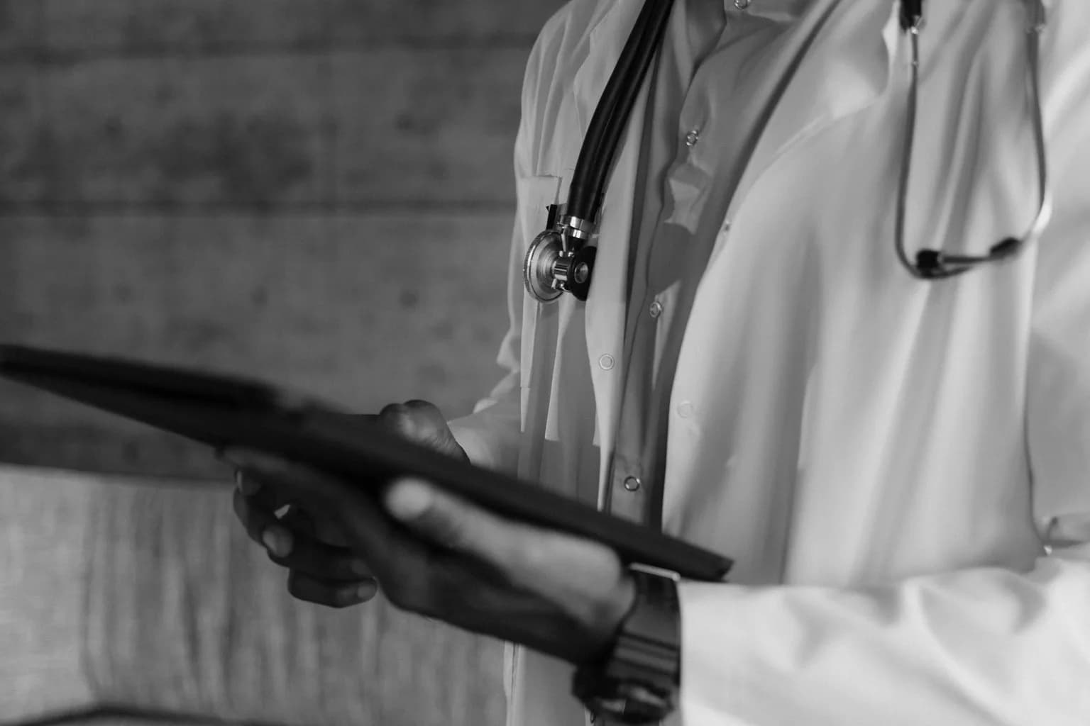 A healthcare worker consults a tablet in a clinical setting in a low-income country.