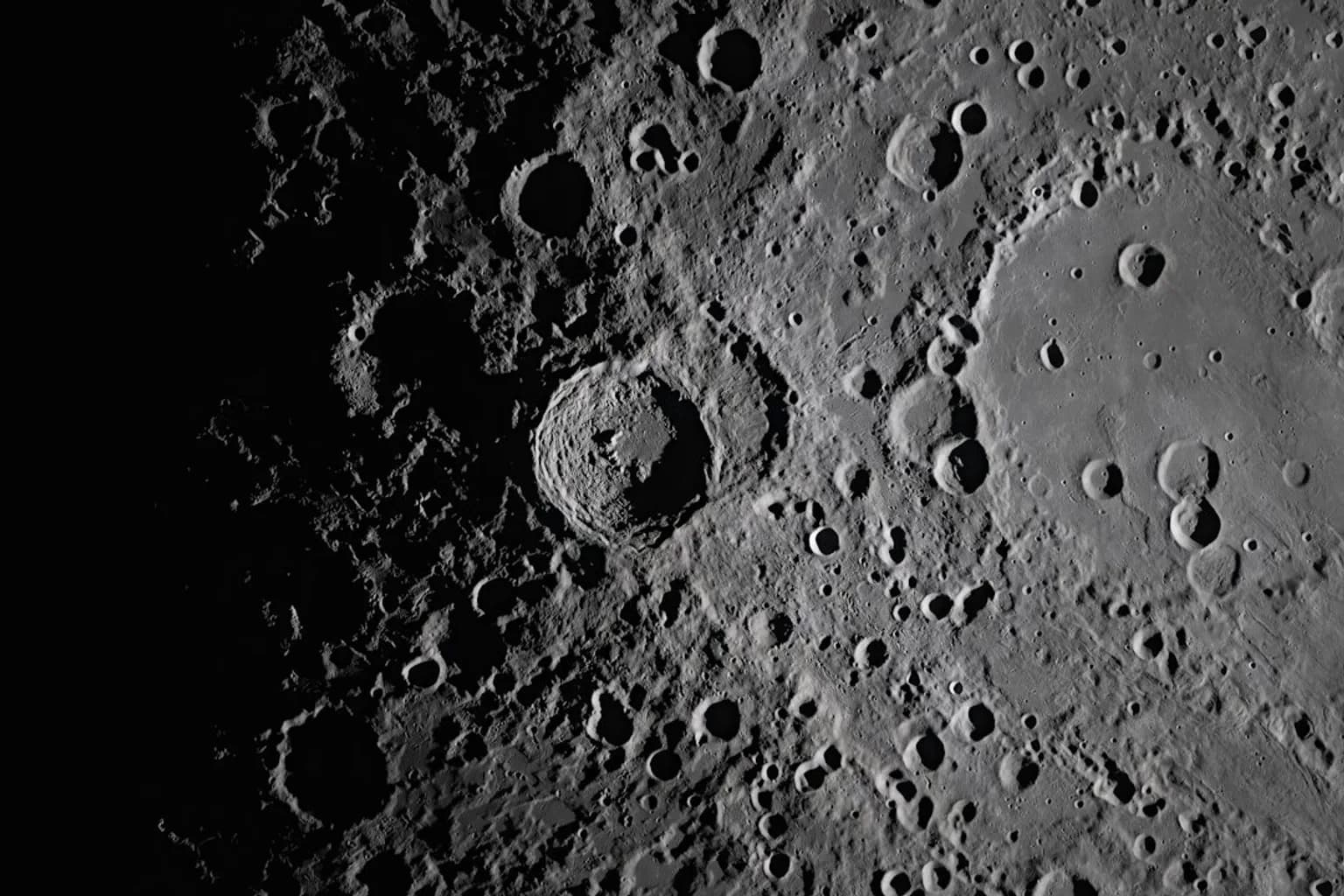 A large, freshly formed impact crater on the Moon's surface surrounded by a bright ejecta halo and darker material