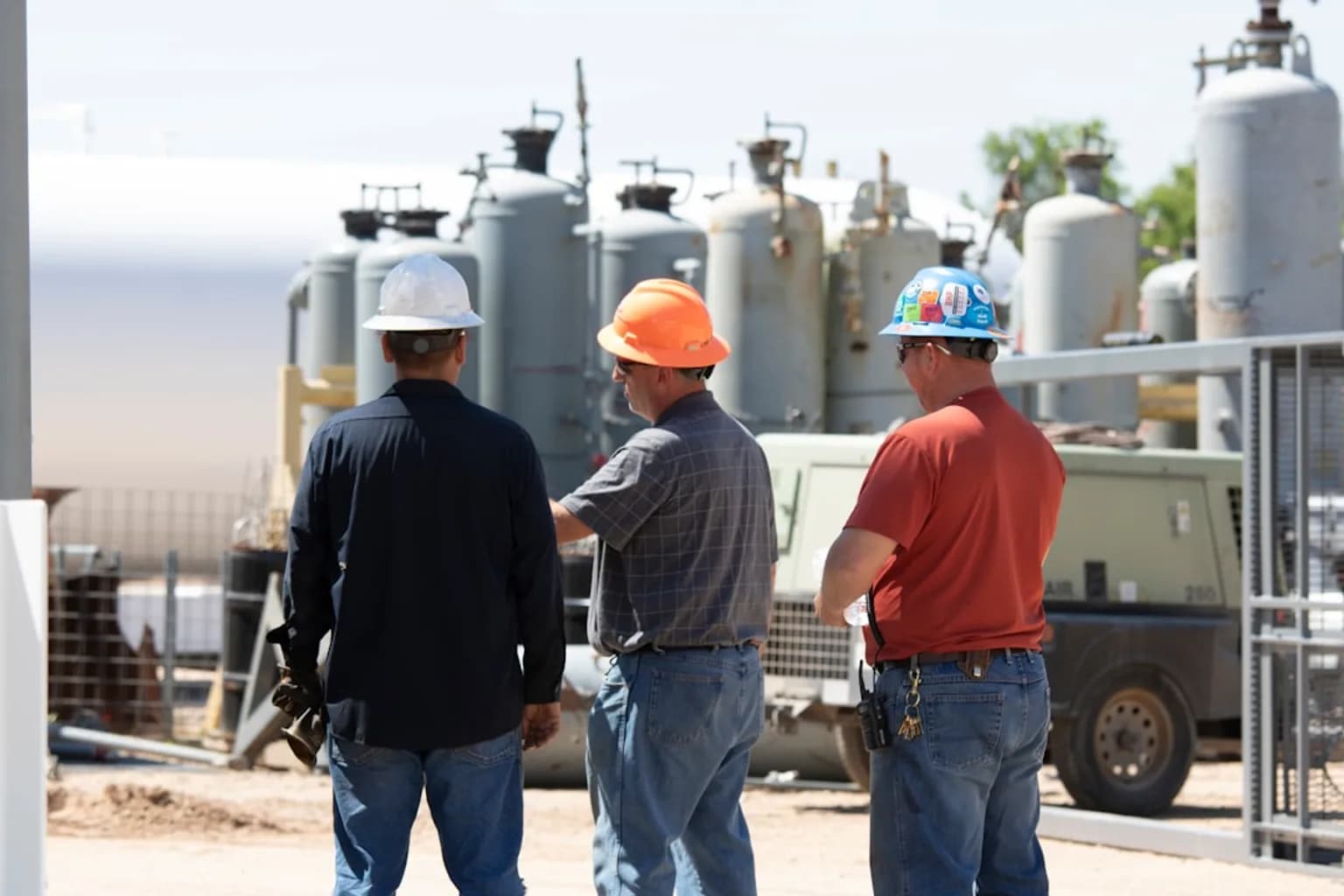 Outdoor construction workers labouring in intense heat, wearing hard hats and high-visibility vests