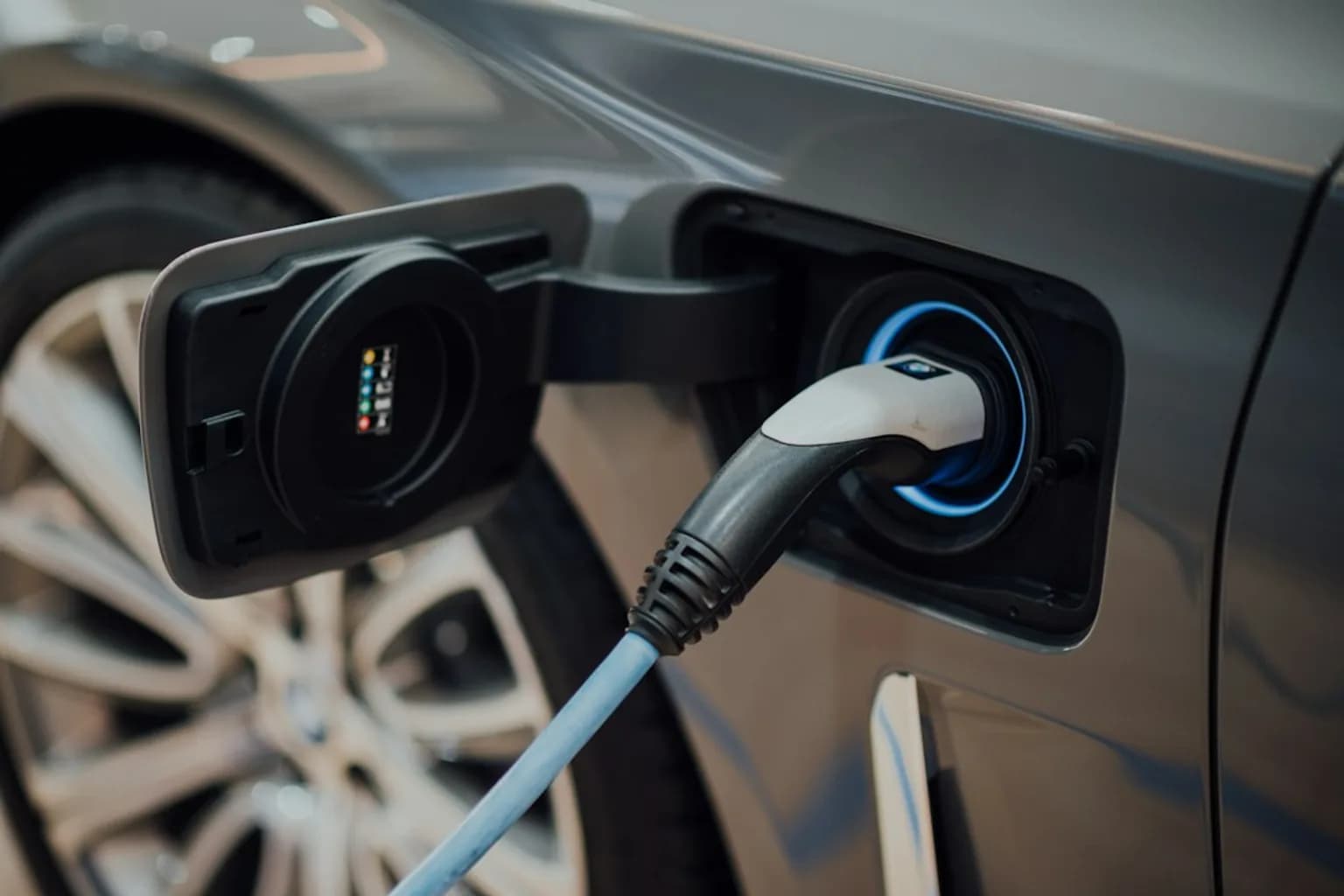 A row of electric vehicles plugged into charging stations at a public charging point.