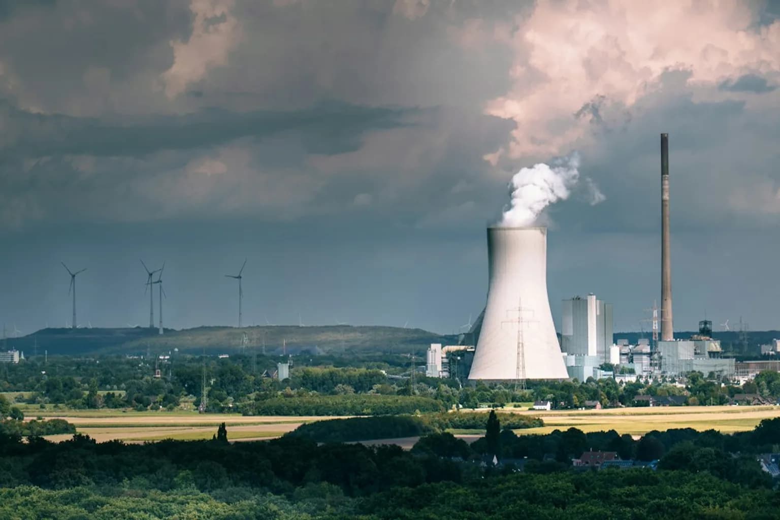 Coal-fired power plant cooling towers emitting steam against an overcast sky