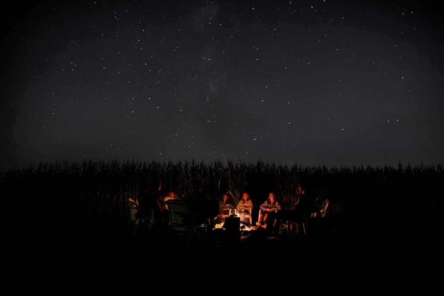 A campfire burning at night with glowing embers and flickering orange flames against darkness
