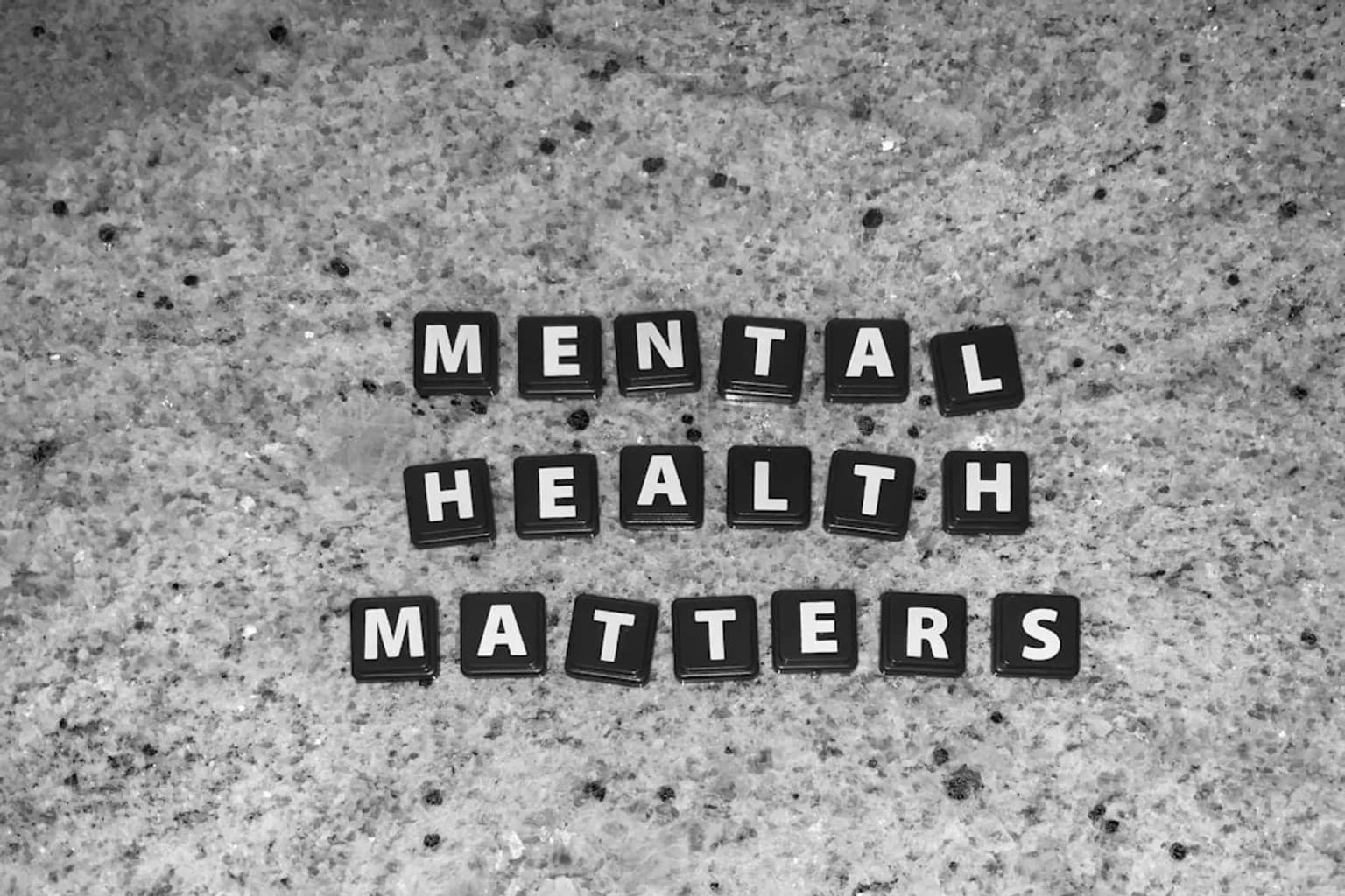 A young person sitting alone in a waiting room, head down, representing youth mental health struggles.