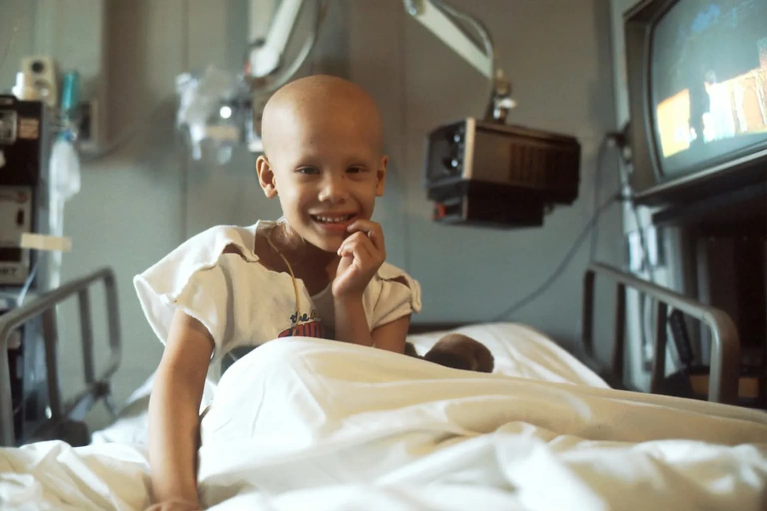 A child receiving medical treatment in a hospital ward, representing the global disparity in childhood cancer survival rates.