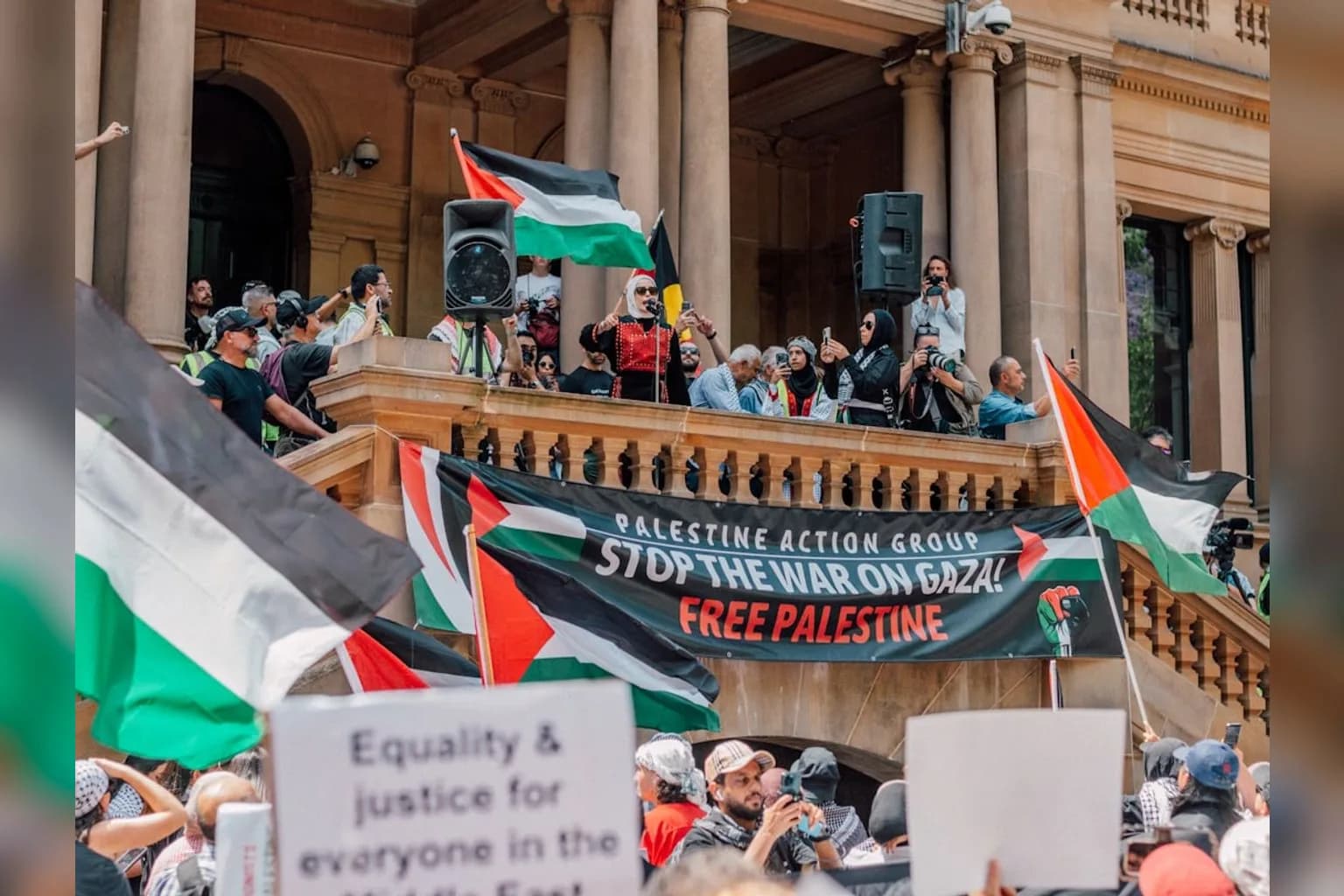 Crowd at a pro-Palestinian rally holding signs and flags