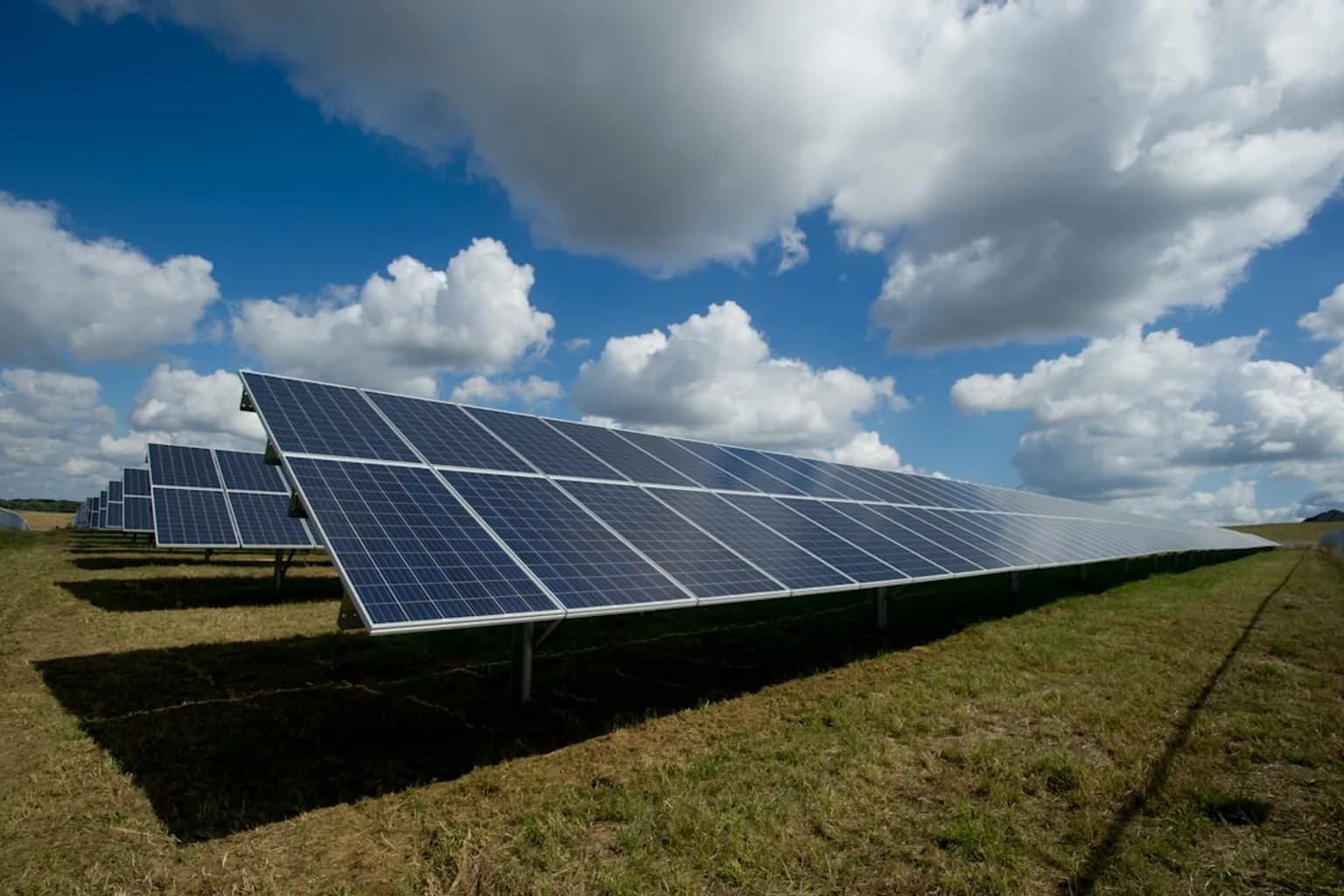 Rows of solar panels at a large utility-scale solar farm under a clear sky