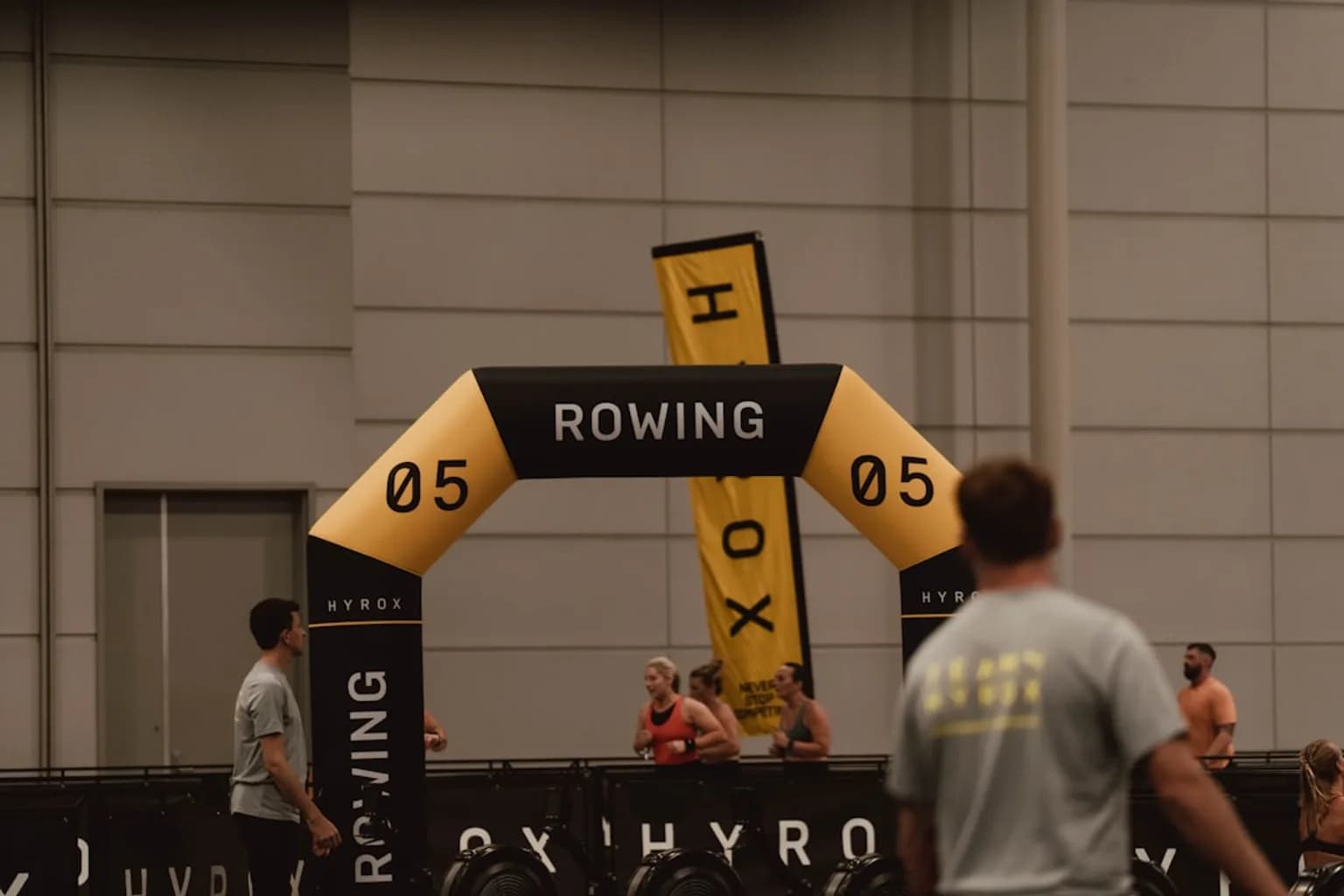 Competitors at a Hyrox indoor fitness event using shared workout equipment