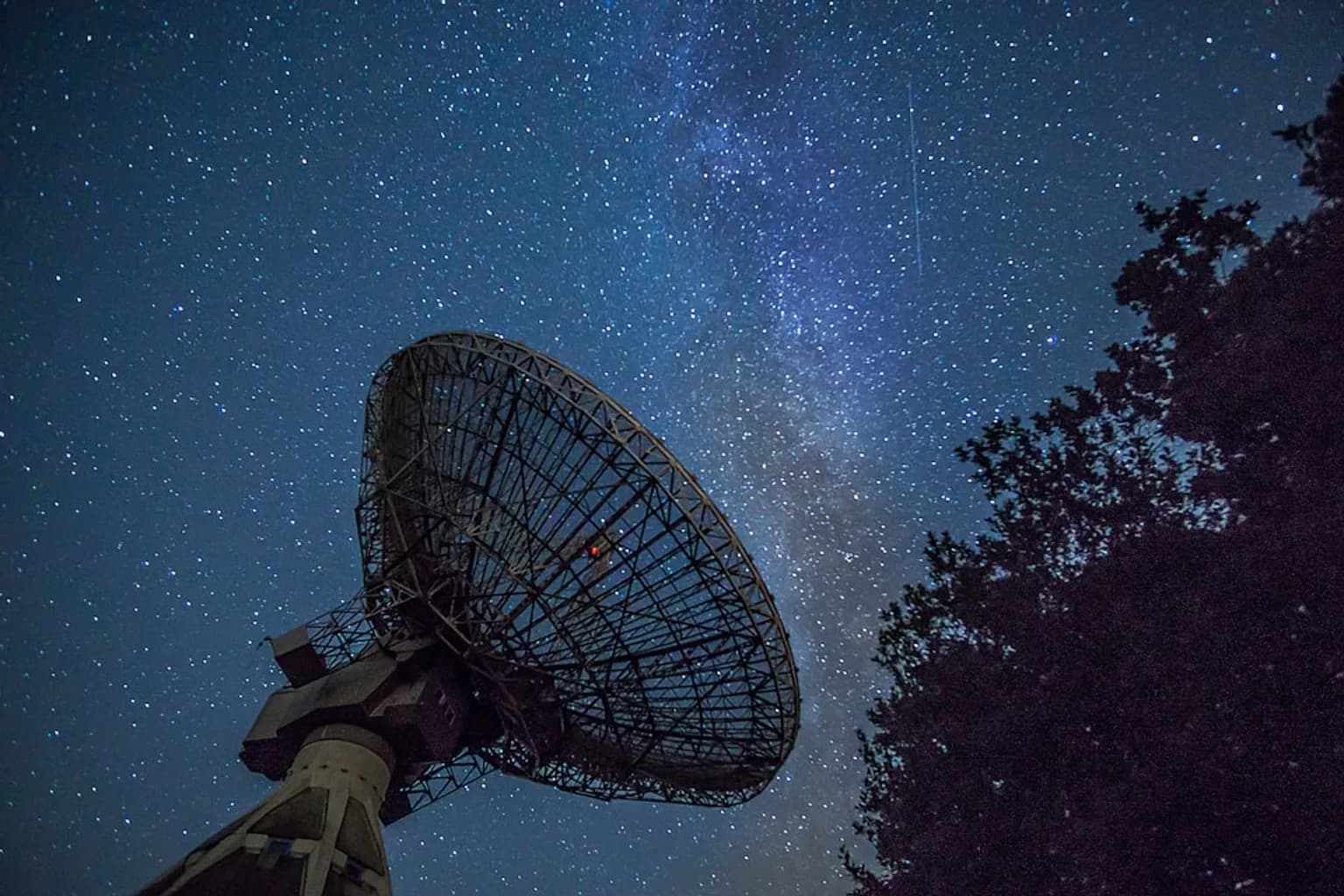 Large radio telescope dishes pointed at the night sky at an observatory