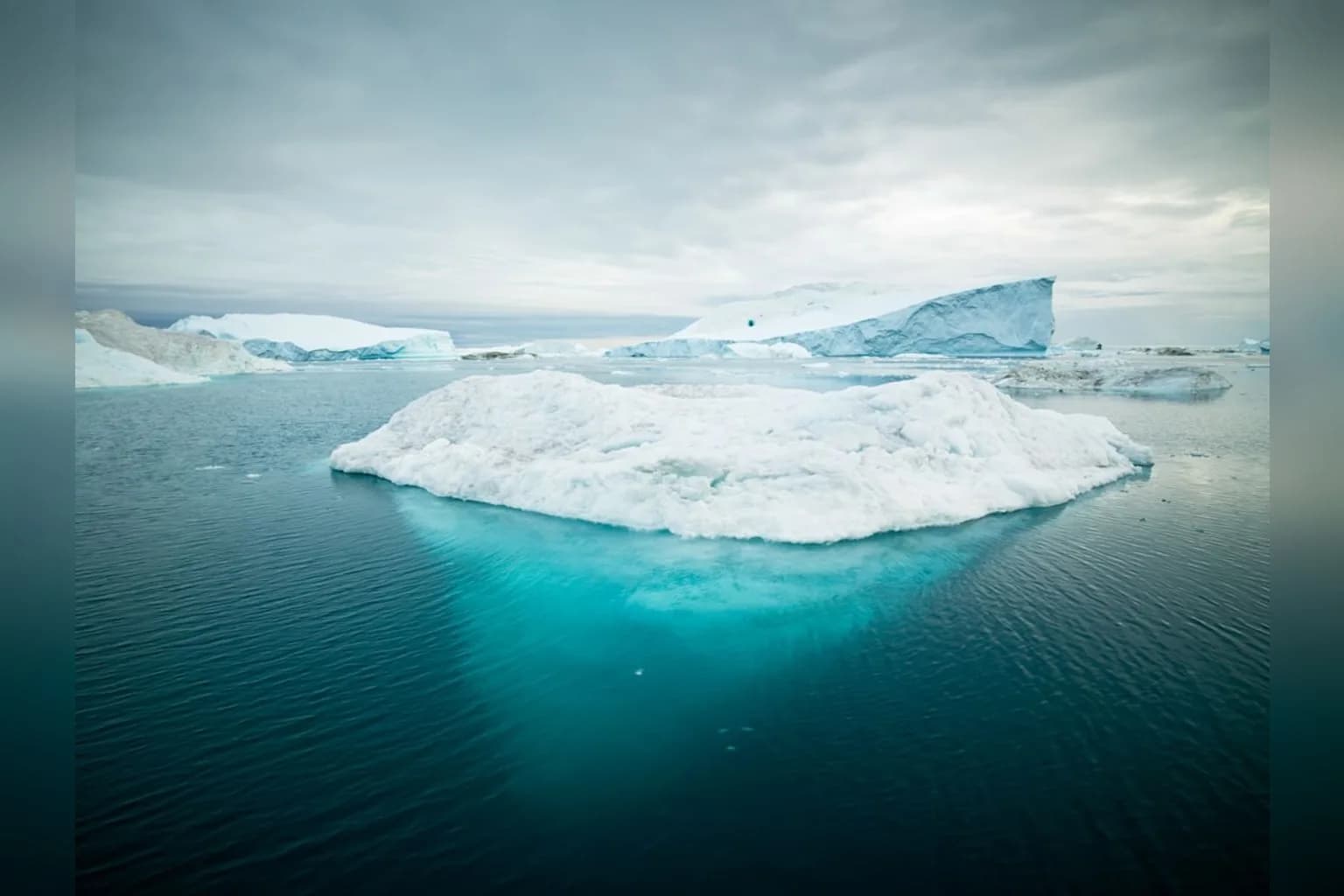 Aerial view of a Greenland glacier showing ice melt and calving into the ocean
